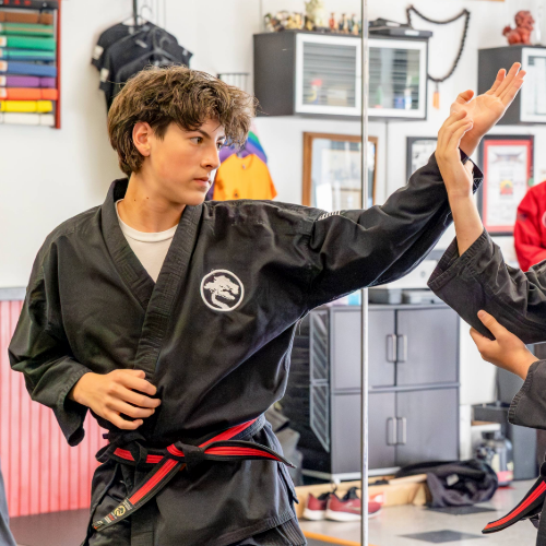 A karate student is practicing a block technique with a fellow student before USSD Livermore karate class begins.