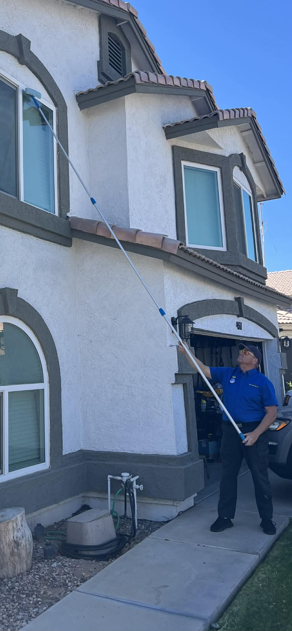 Man in yellow CFTO shirt cleaning the glass door of Falcon Field building in Mesa, Arizona.