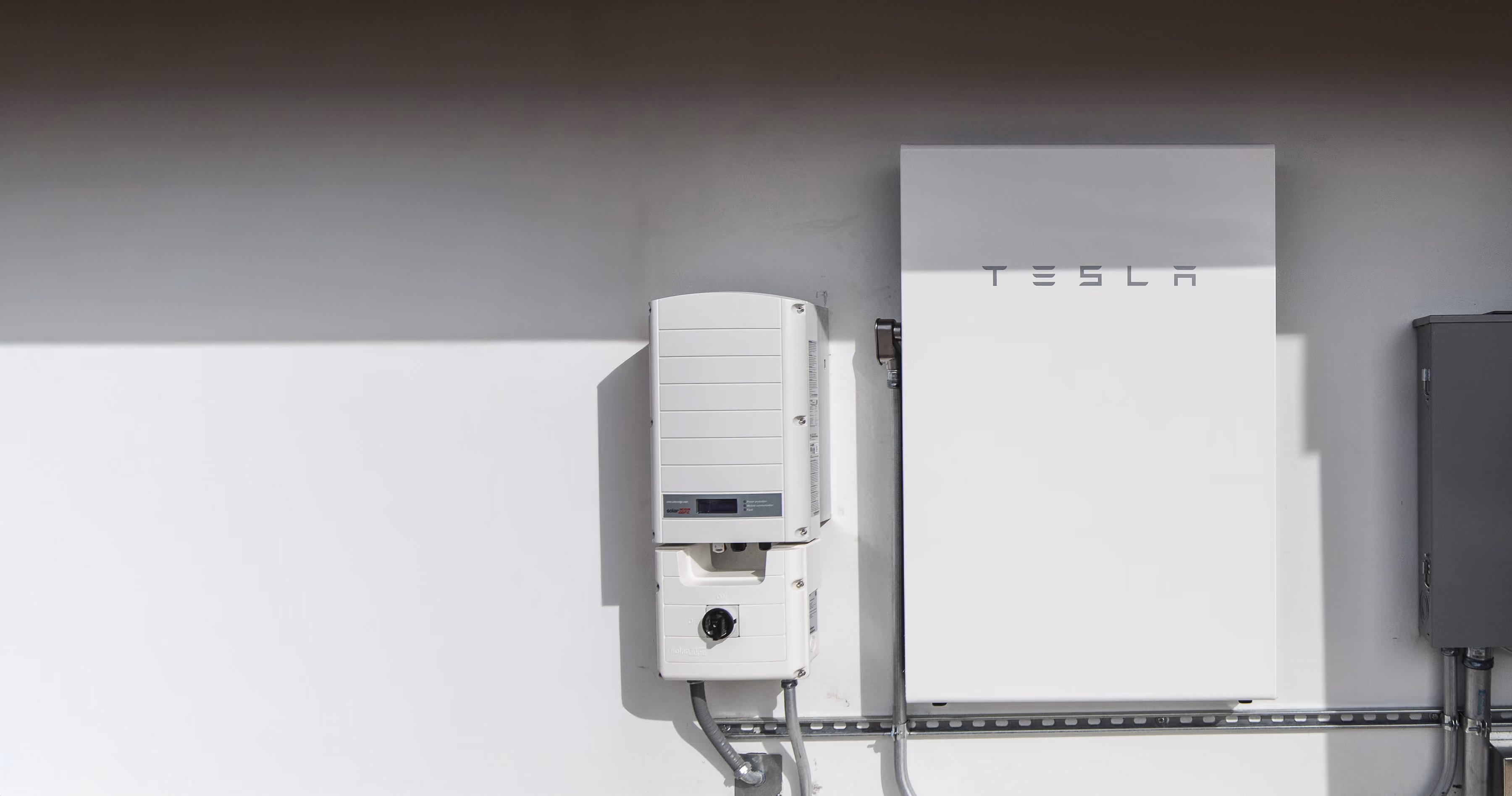 A wall-mounted home battery and solar inverter installed in a residential utility space.