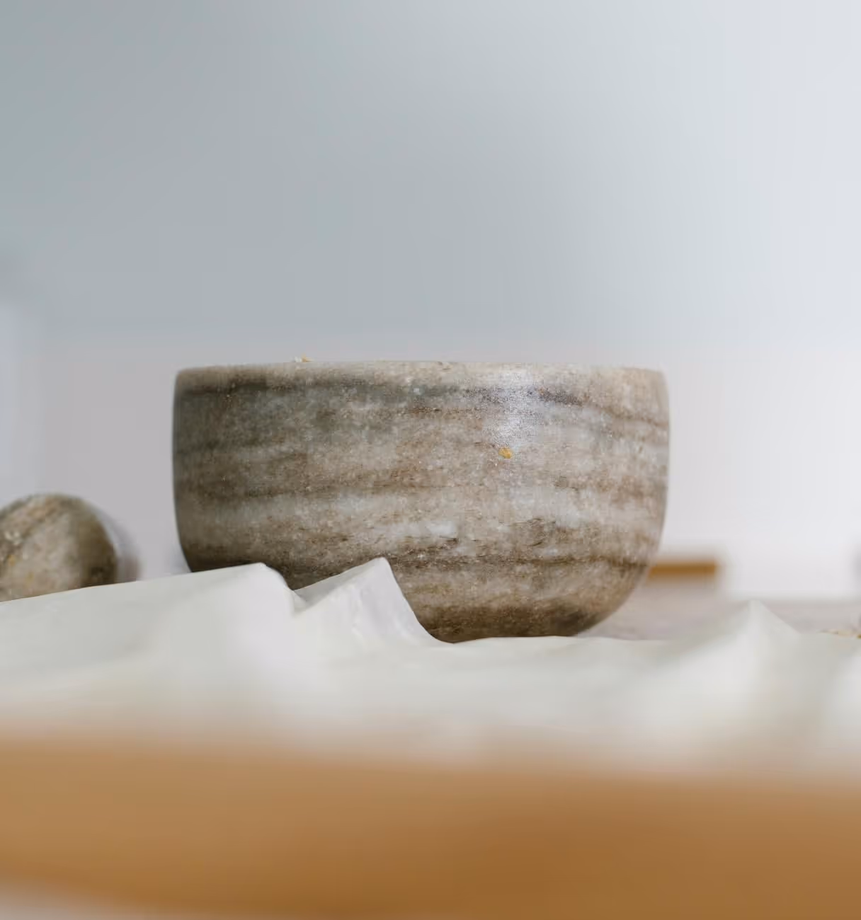 Close-up of a smooth, round granite bowl with natural brown and gray patterns on a soft white cloth.