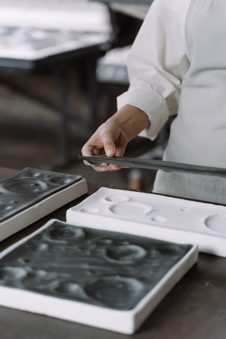 Person in white shirt handling black and white molds on a table.