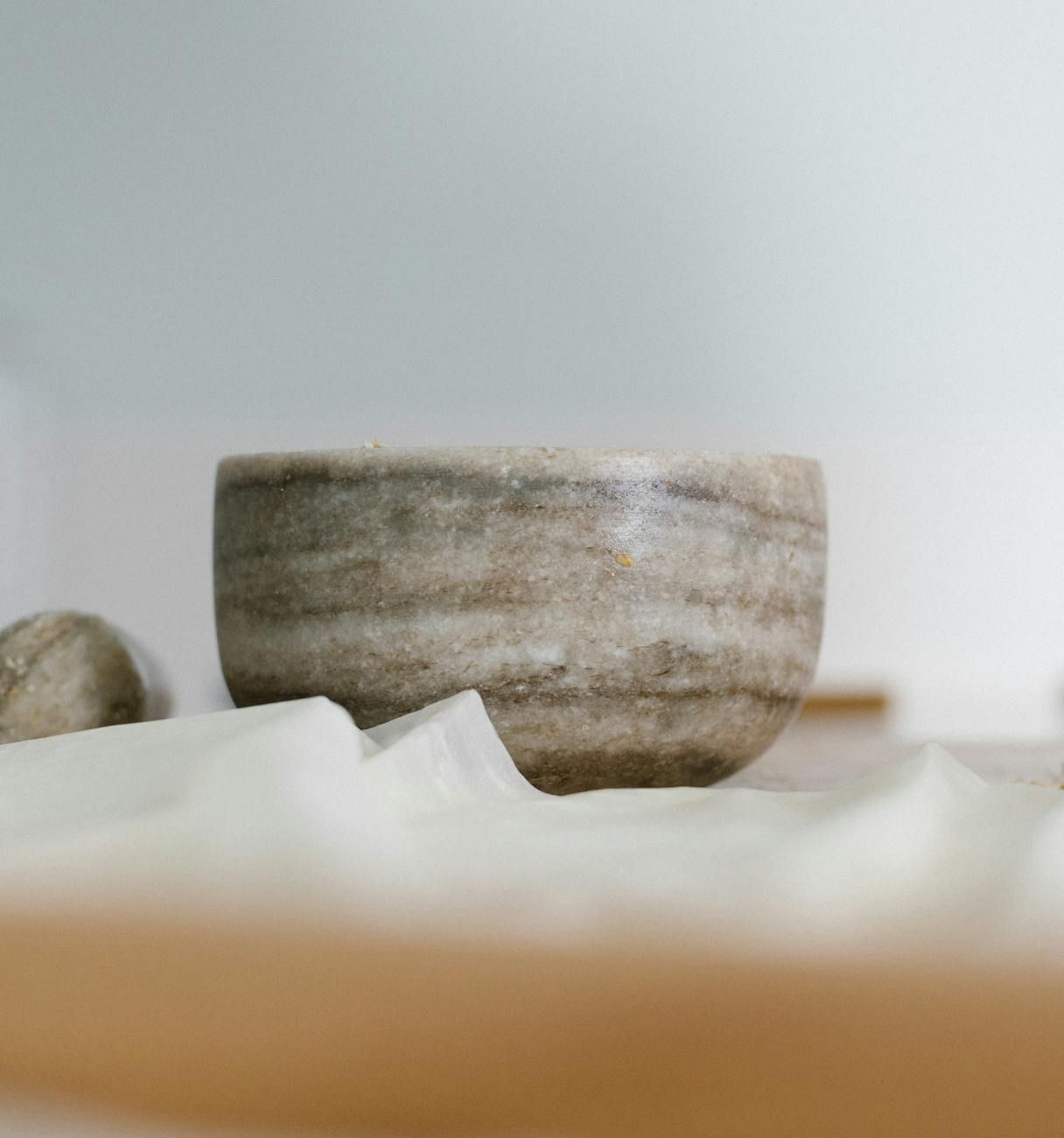Close-up of a smooth, round marble bowl with natural stone veining on a white cloth surface.