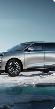 Silver modern SUV parked on snowy ground near icy water under a clear sky.