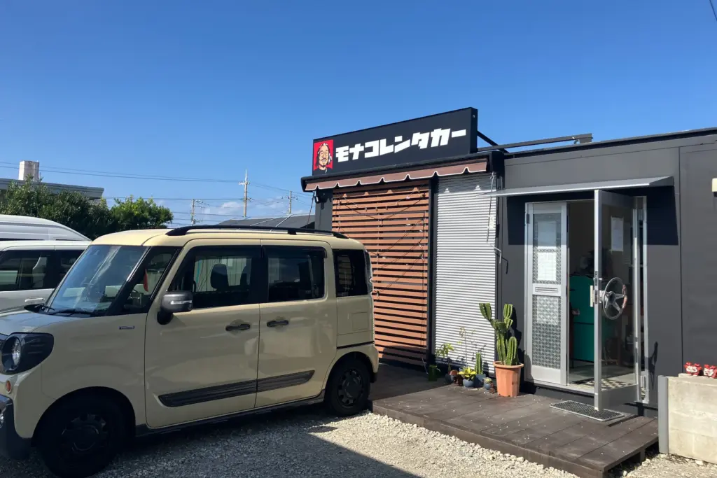 店長の顔が描かれた看板が目印の沖縄・豊見城市のモナコレンタカー様の店舗