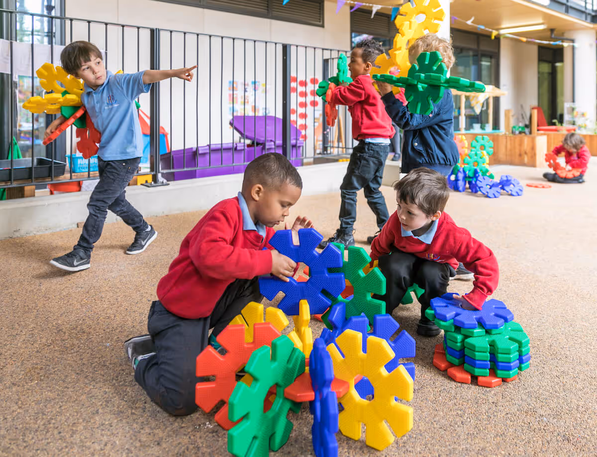 Children are engrossed in playing with colourful large building blocks, creating interesting shapes as they stack them.