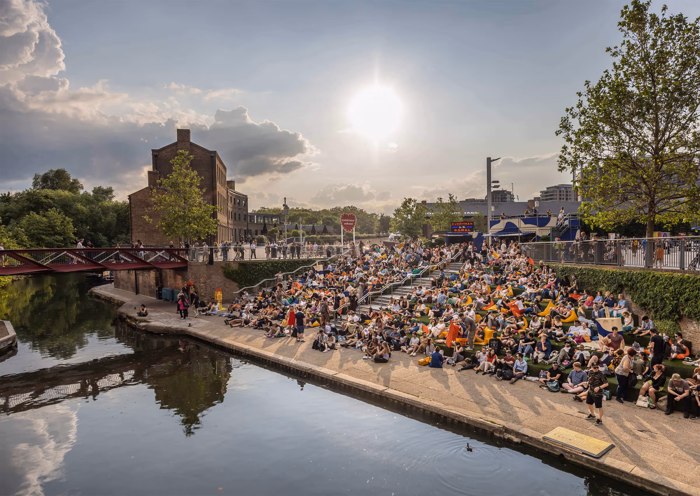 People sit alongside the canal in the late evening to watch a movie at King's Cross summer 'Screen on the Canal' event