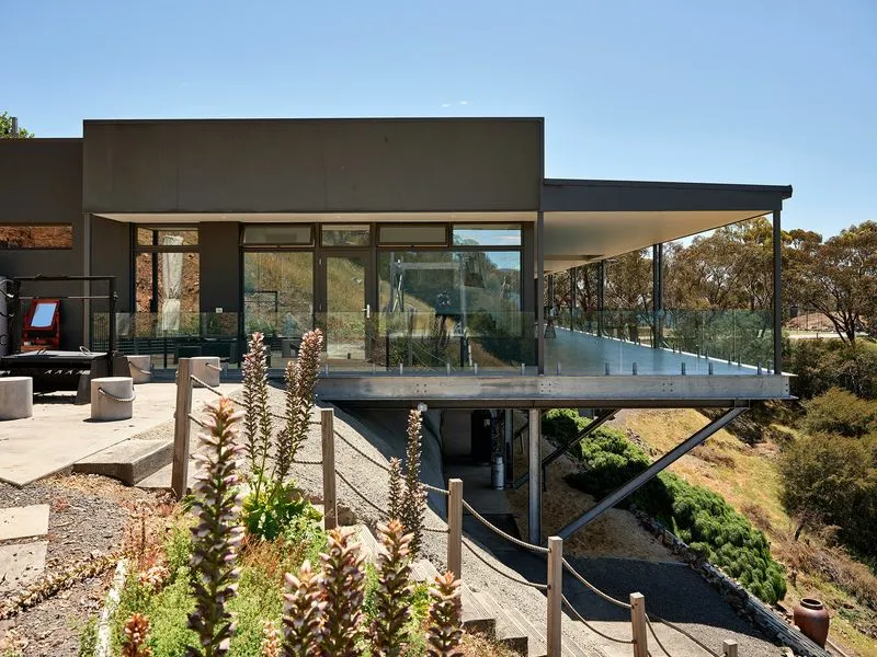 Modern house with elevated glass balcony and hillside view