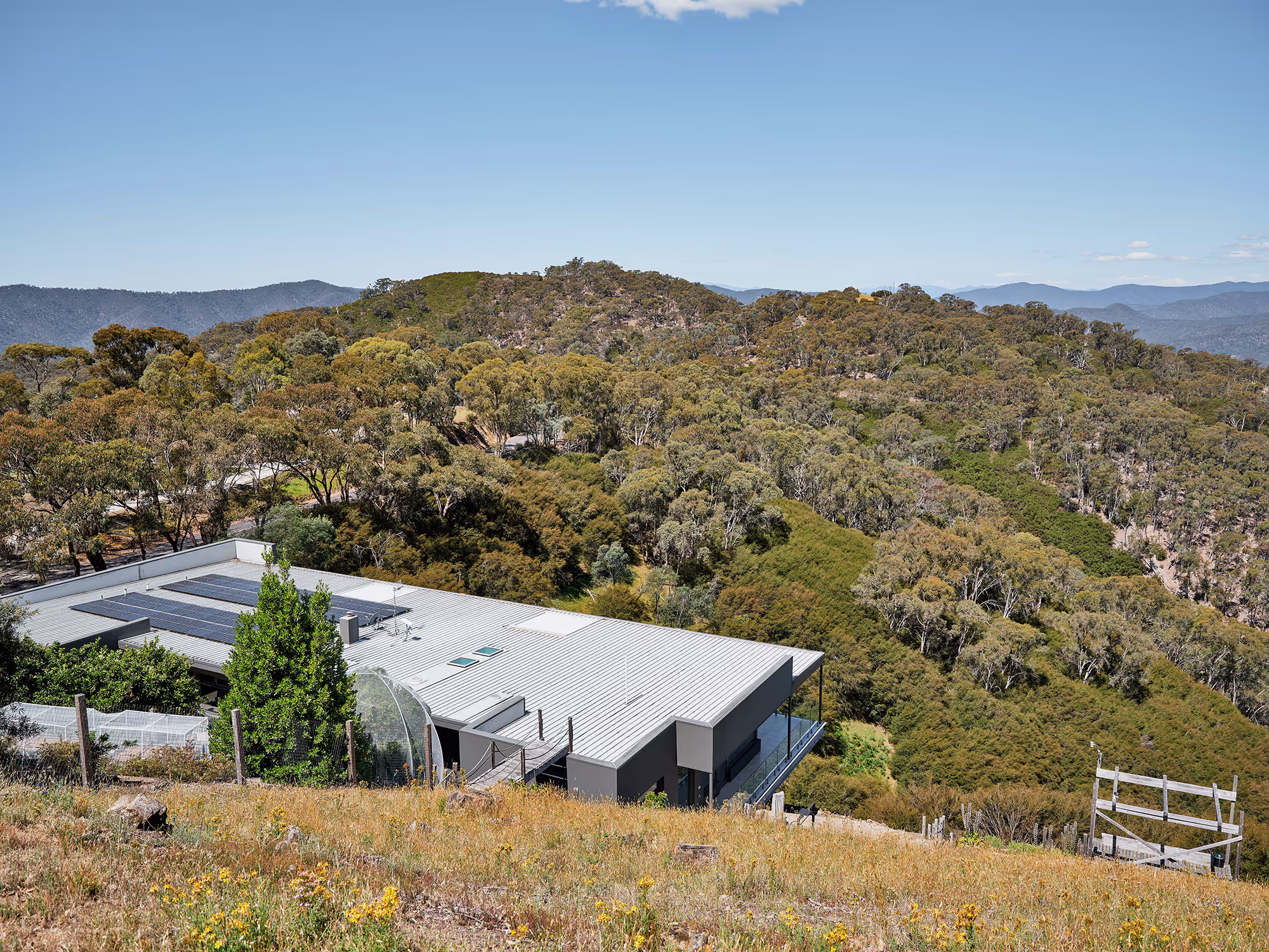 House with solar panels surrounded by forested hills