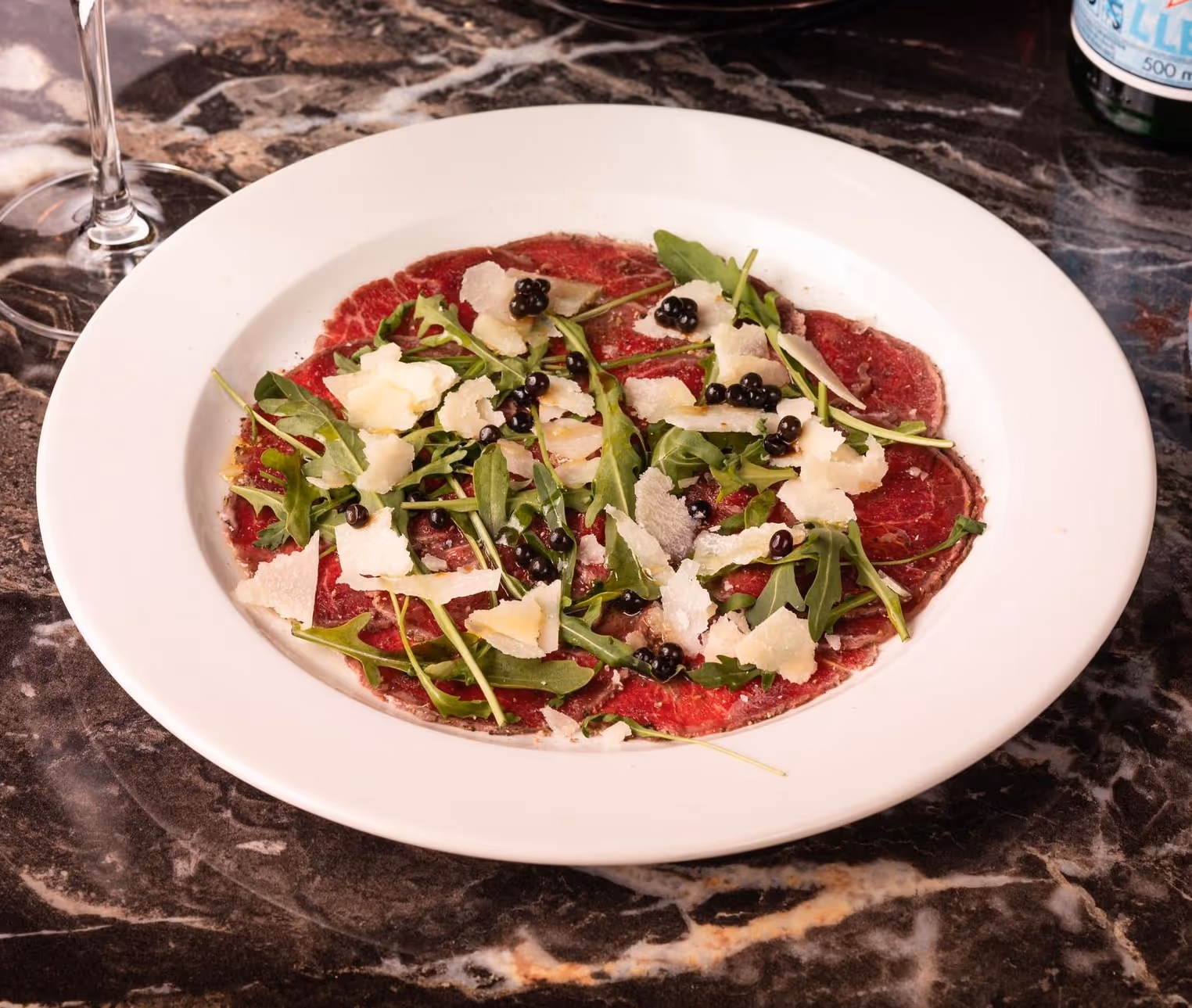 Carpaccio di Manzo med tynne skiver av okse, ruccola, parmesan og balsamico – servert hos Riviera Restaurant i Oslo
