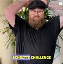 Mann mit Bart und Mütze steht mit erhobenen Armen vor einer Pflanze