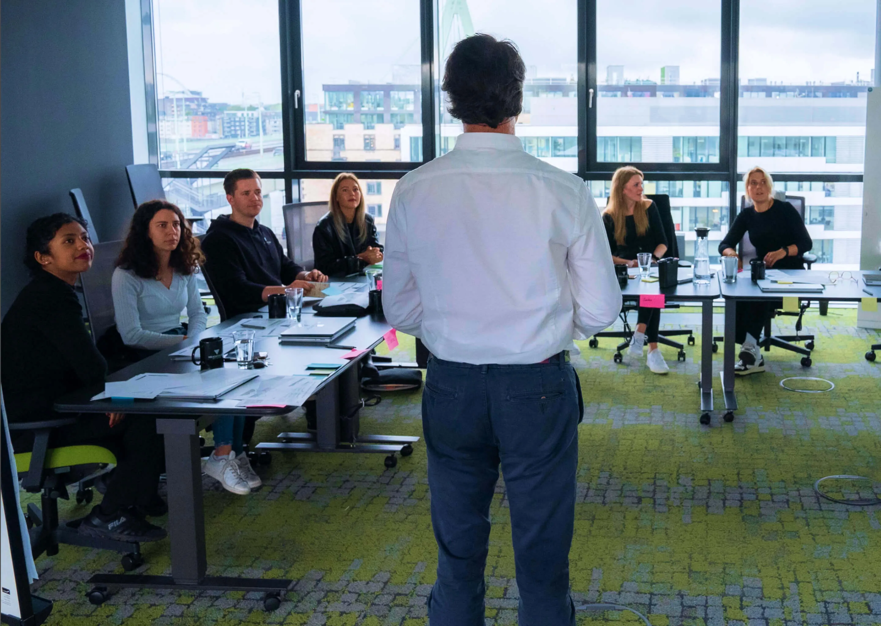 Nikolai Ladanyi, mit dem Rücken zur Kamera, blickt auf eine aufmerksame Menschenmenge während eines quartalsweisen Workshops, organisiert von Headfound.