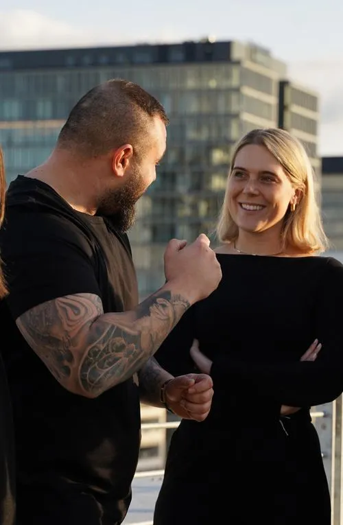 Gespräch zwischen Jan Truch und einer Mitarbeiterin draußen unterhalb des Microsoft-Gebäudes in Köln, mit Ausblick auf die Kranhäuser bei Sonnenuntergang. Jan gestikuliert mit seiner Hand