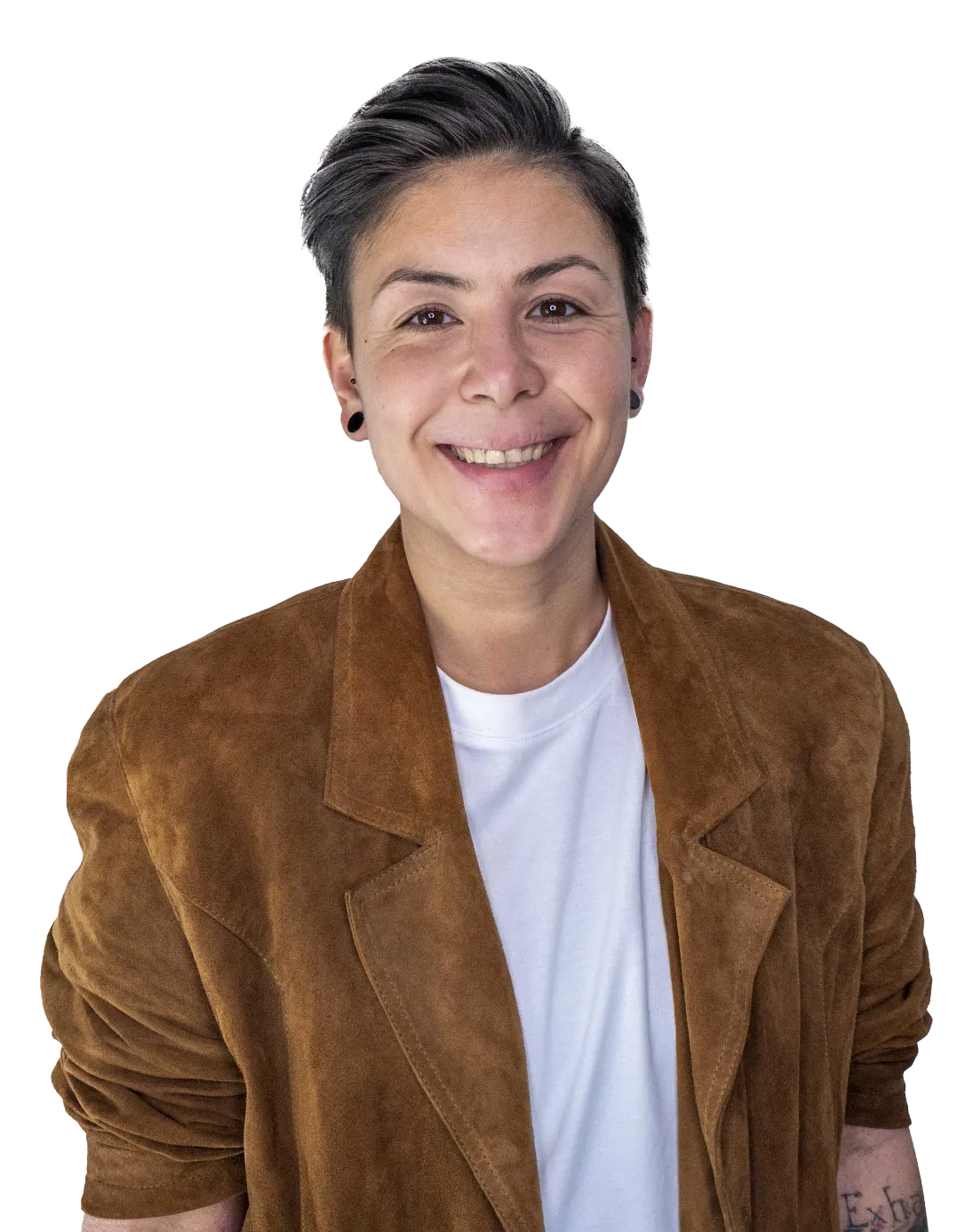 Person mit kurzem dunklem Haar, brauner Jacke und weißem T-Shirt lächelt in die Kamera