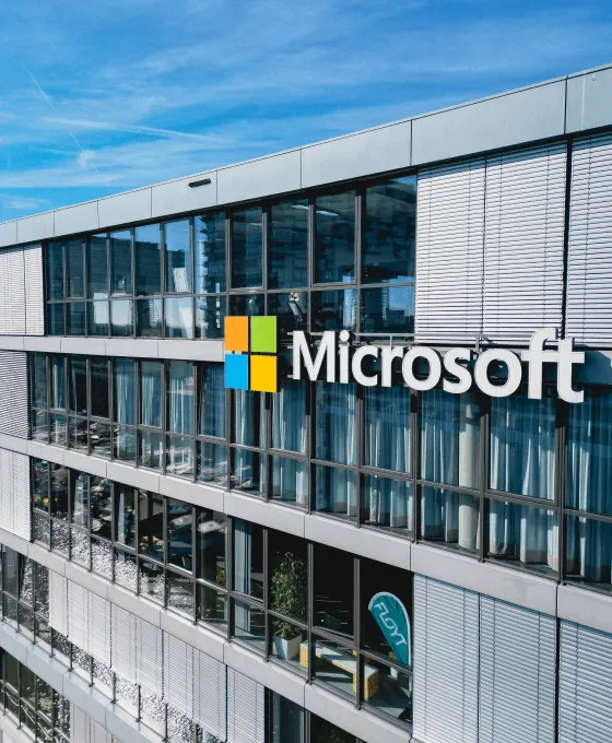 Moderne Glasfassade eines Microsoft Bürogebäudes bei Tageslicht mit blauem Himmel im Hintergrund