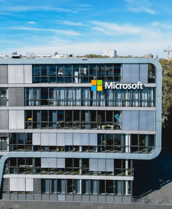 Moderne Microsoft-Gebäudefassade mit Glasfront und Firmenlogo bei blauem Himmel