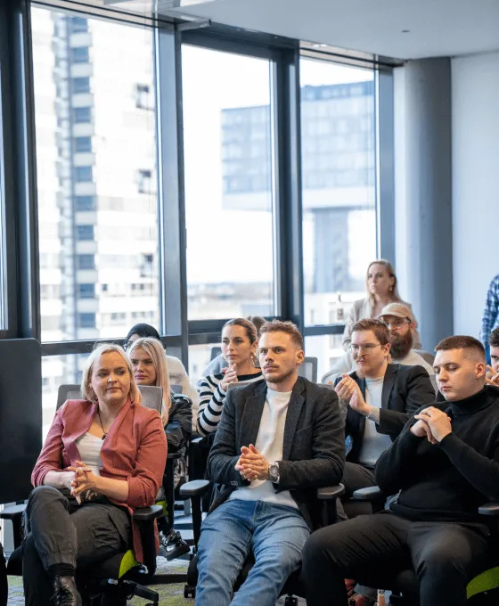Gruppe junger Menschen applaudiert bei einer Präsentation im modernen Büro 