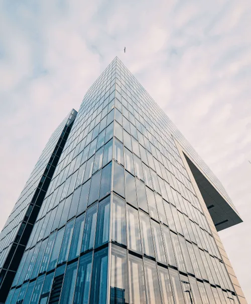 Modernes Hochhaus mit Glasfassade vor bewölktem Himmel