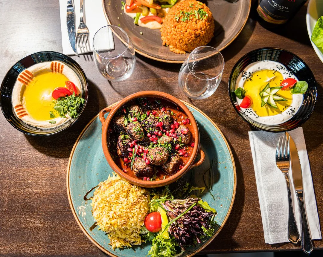 Midtøstens smaker servert på en fargerik tallerken hos KosKos: grillet kafta med granateple, krydret ris, hummus og frisk salat – omgitt av autentiske meze-retter.