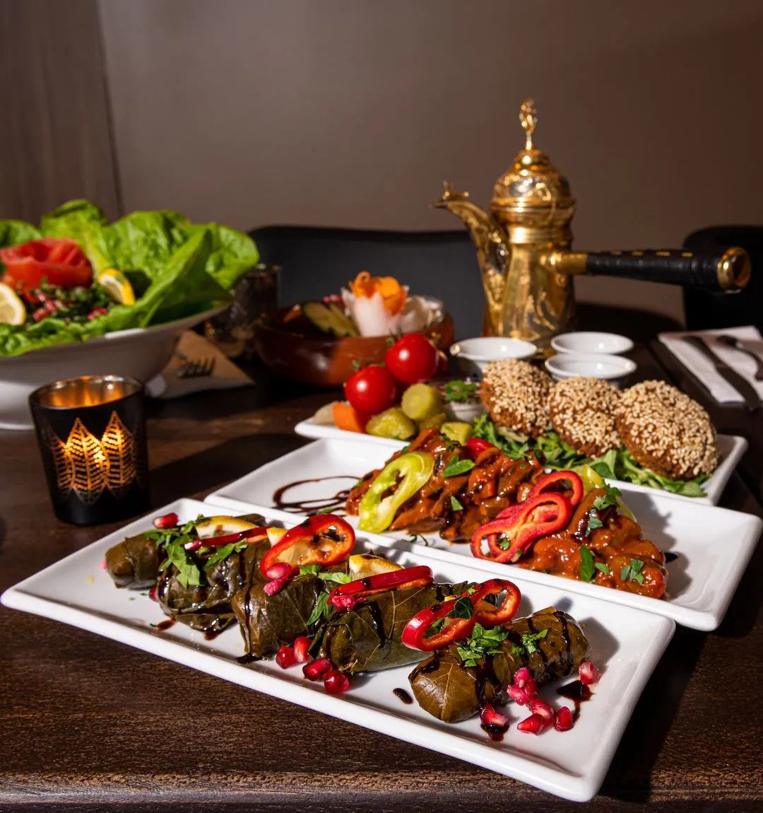 Et elegant meze-bord hos KosKos med vinblader fylt med ris, falafel med sesam, krydrede kjøttretter og tabbouleh – servert med arabisk kaffekanne og dekorativ lykt.