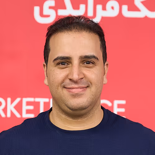 Smiling man with short dark hair wearing a navy blue shirt against a red background with white text.