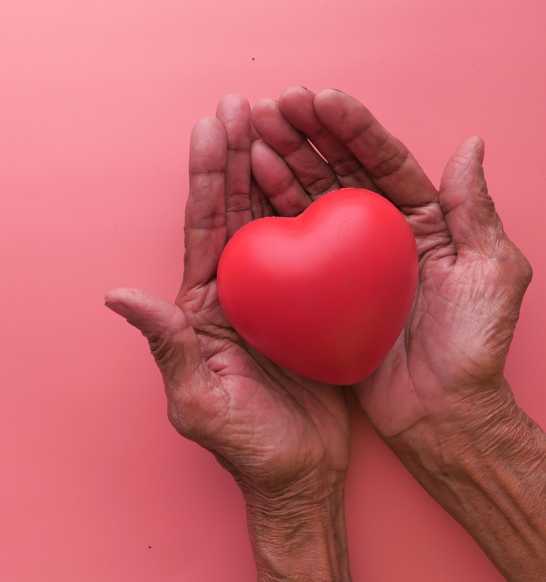 Two hands gently holding a heart shaped object