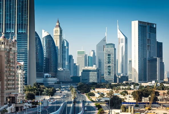 Modern Dubai skyline with Emirates Towers, clock tower, and high-rise buildings along Sheikh Zayed Road on a clear day.