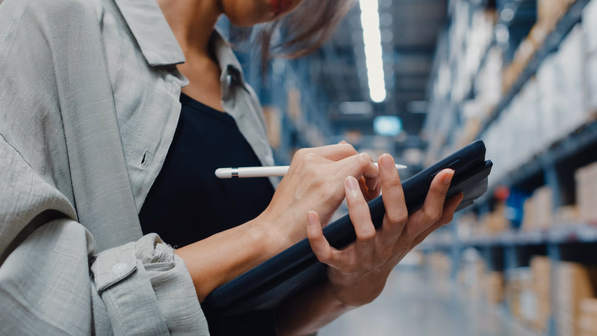 Warehouse worker using digital tablet for inventory management and logistics control in a modern storage facility.