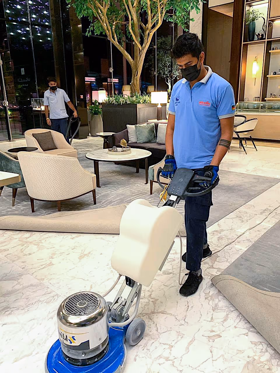 Professional cleaner polishing marble floor with industrial machine in a luxury hotel lobby, ensuring high shine and stone surface protection.