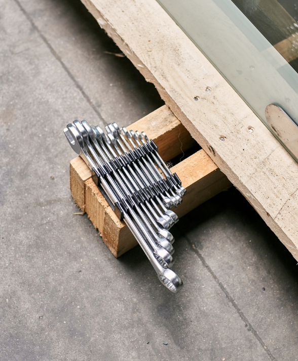 Une série de clés mixtes en métal alignées et attachées ensemble, posées sur un morceau de bois à côté d'une palette en bois.