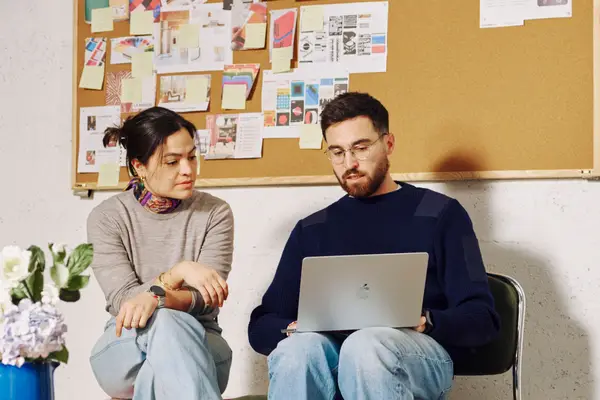 Homme utilisant une cabine insonorisée dans une salle de réunion moderne avec table bleue et chaises grises.