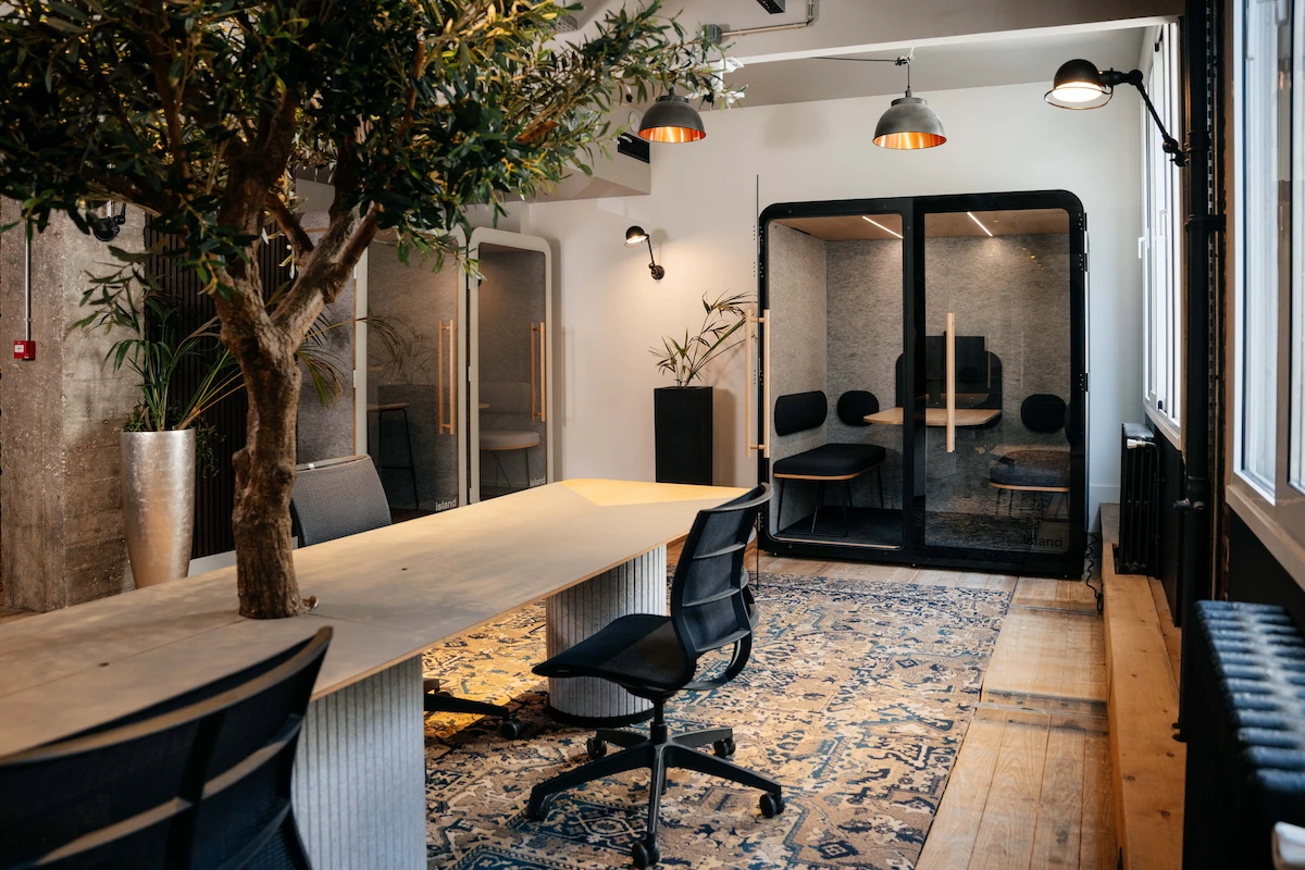 Bureau avec une table, un arbre, et des cabines acoustiques