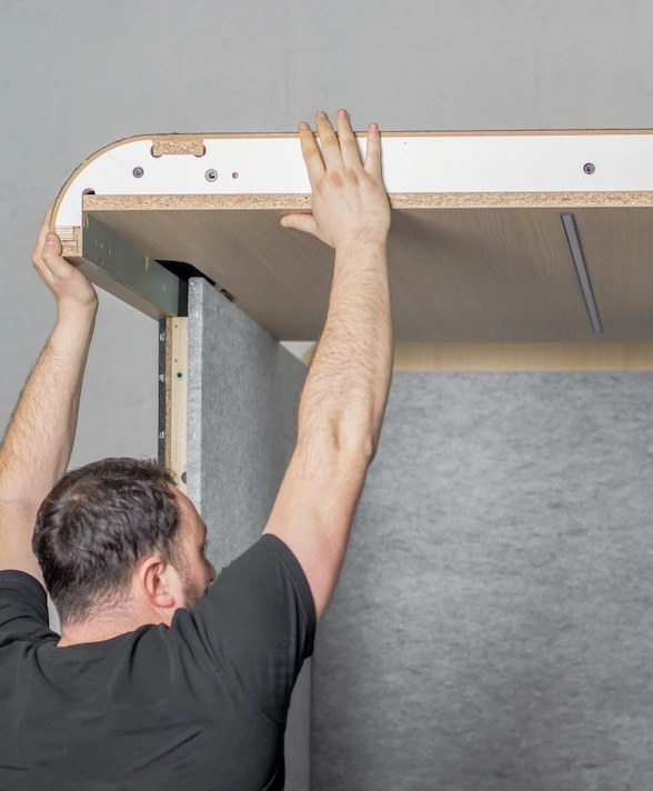 Personne en train de réaliser le montage d'une cabine acoustique.