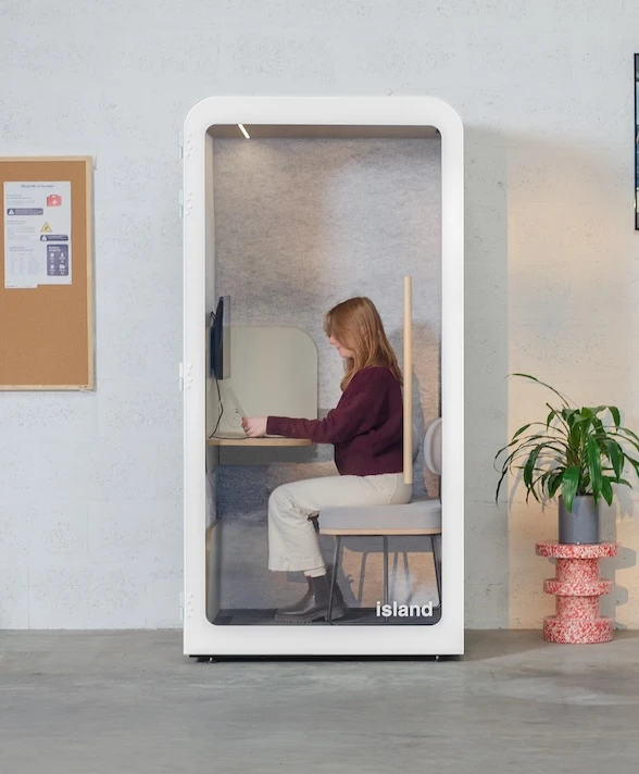 Femme travaillant dans une cabine acoustique de couleur blanche avec écran
