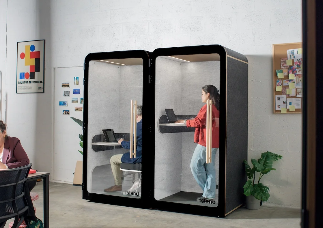 2 personnes qui travaillent dans deux phonebox acoustiques individuelles