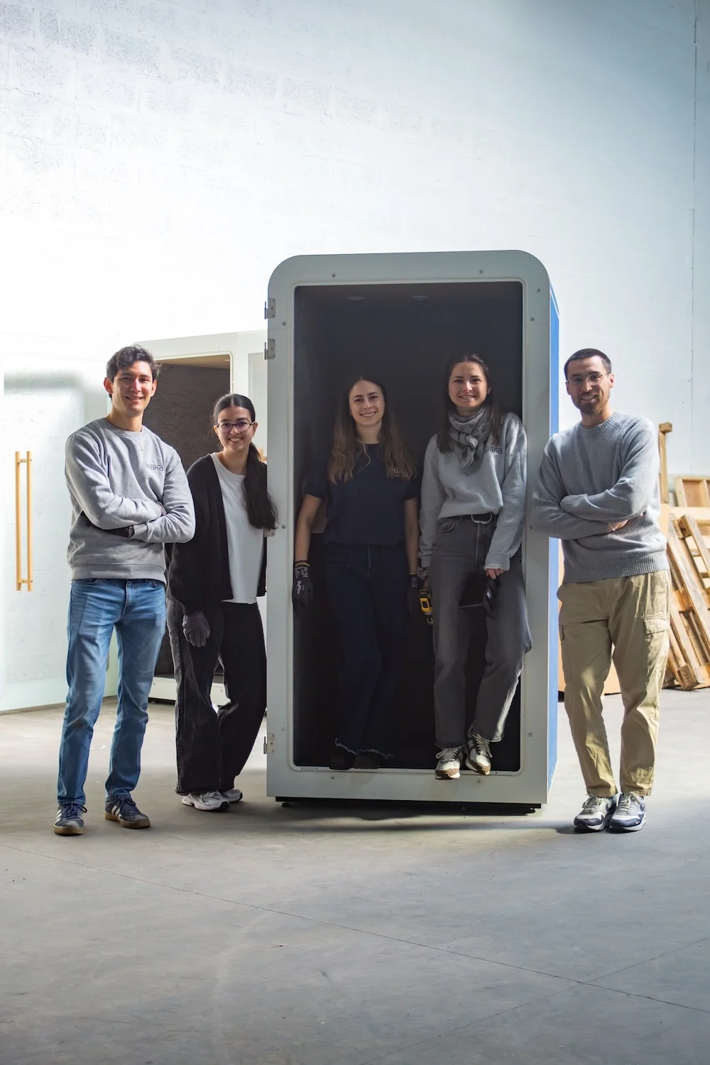 Équipe Work With Island posant autour d'une cabine acoustique blanche en cours de fabrication au Fablab