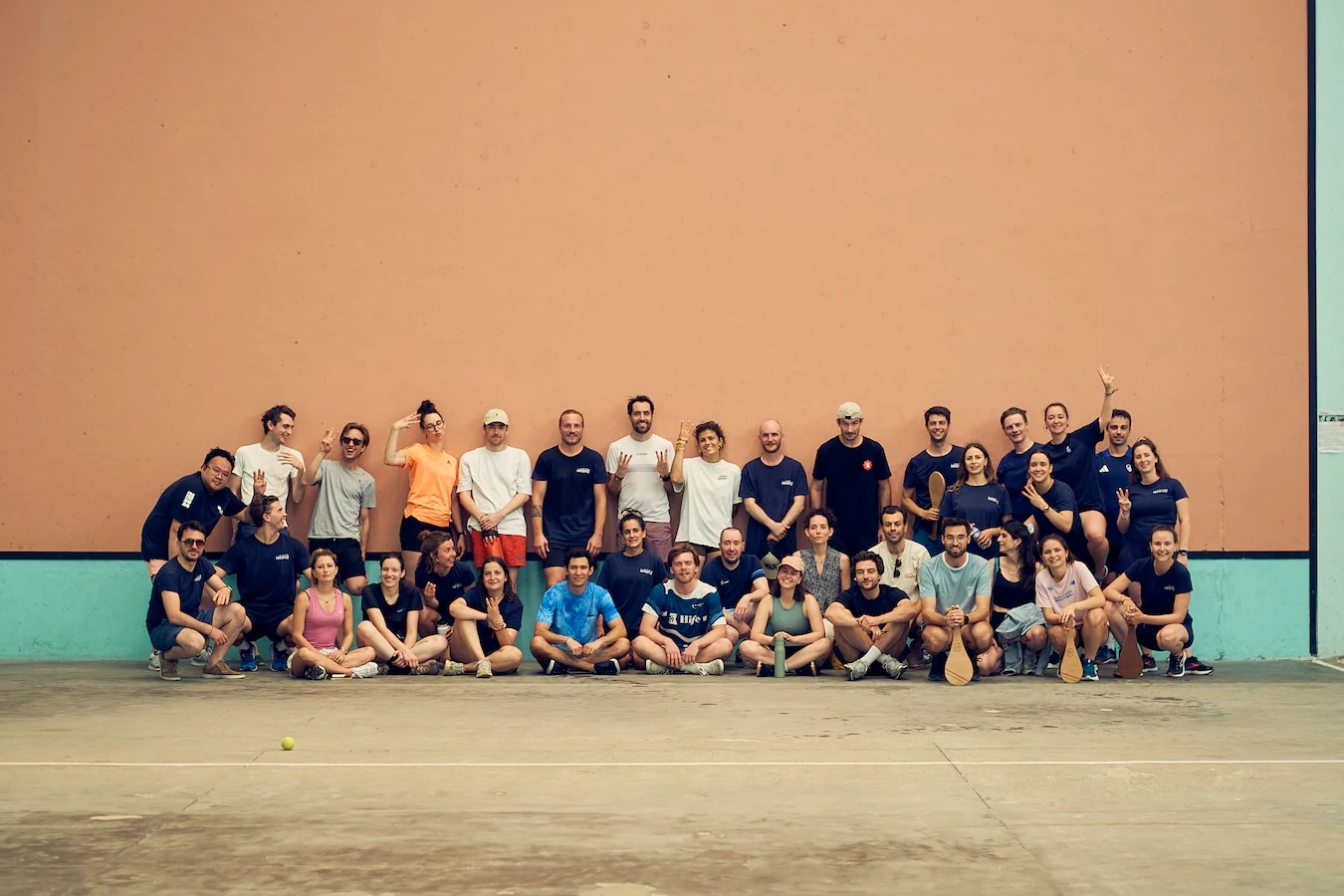 Équipe Work With Island réunie à Biarritz lors du séminaire d'été 2025, devant un mur de fronton