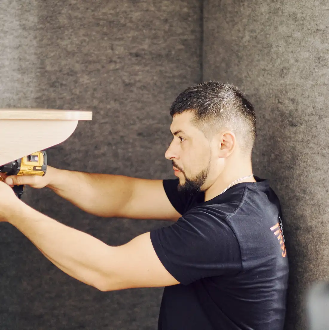 Technicien fixant la tablette d'une cabine acoustique Island à la visseuse chez le client Oatly à Paris