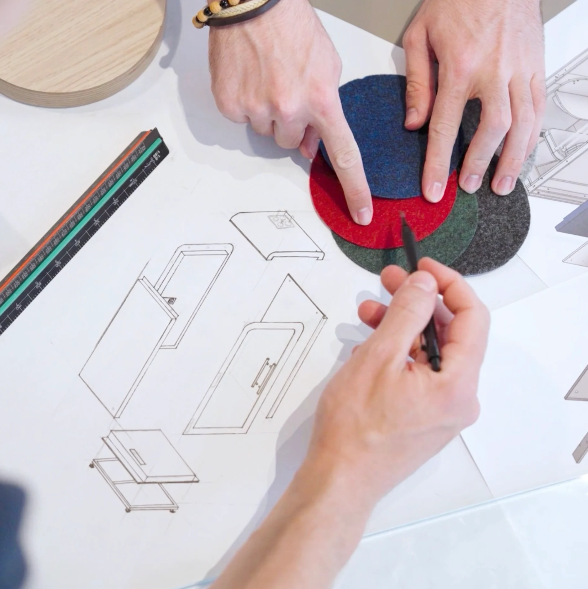 Designer choisissant des échantillons de coloris feutre sur un croquis technique de cabine acoustique Island