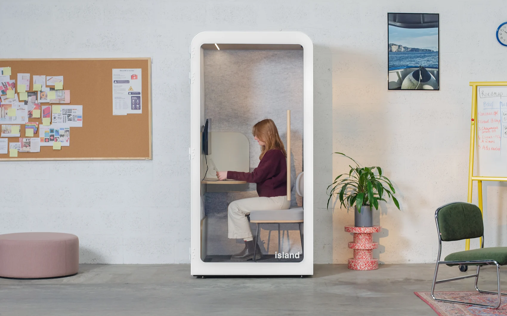 Cabine acoustique Island Solo blanche avec une collaboratrice assise face à un écran connecté