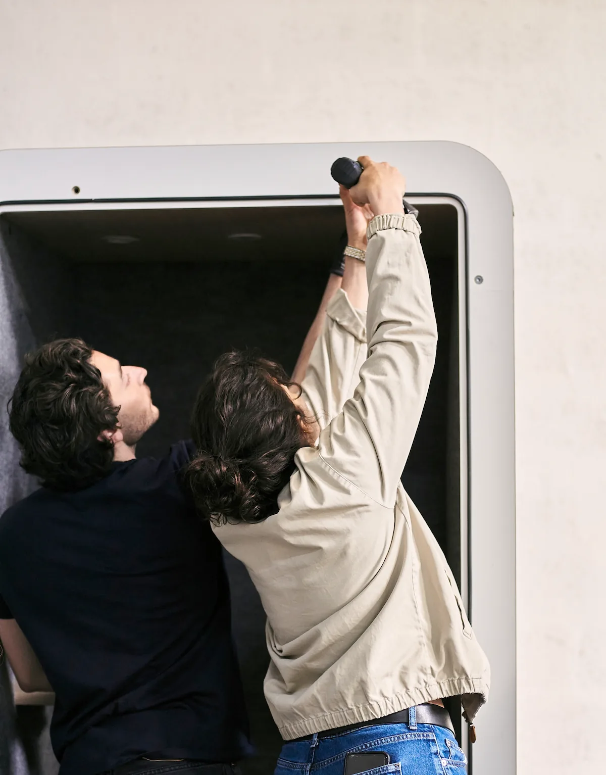 Deux membres de l'équipe Work With Island fixant l'éclairage intérieur d'une cabine acoustique au Fablab
