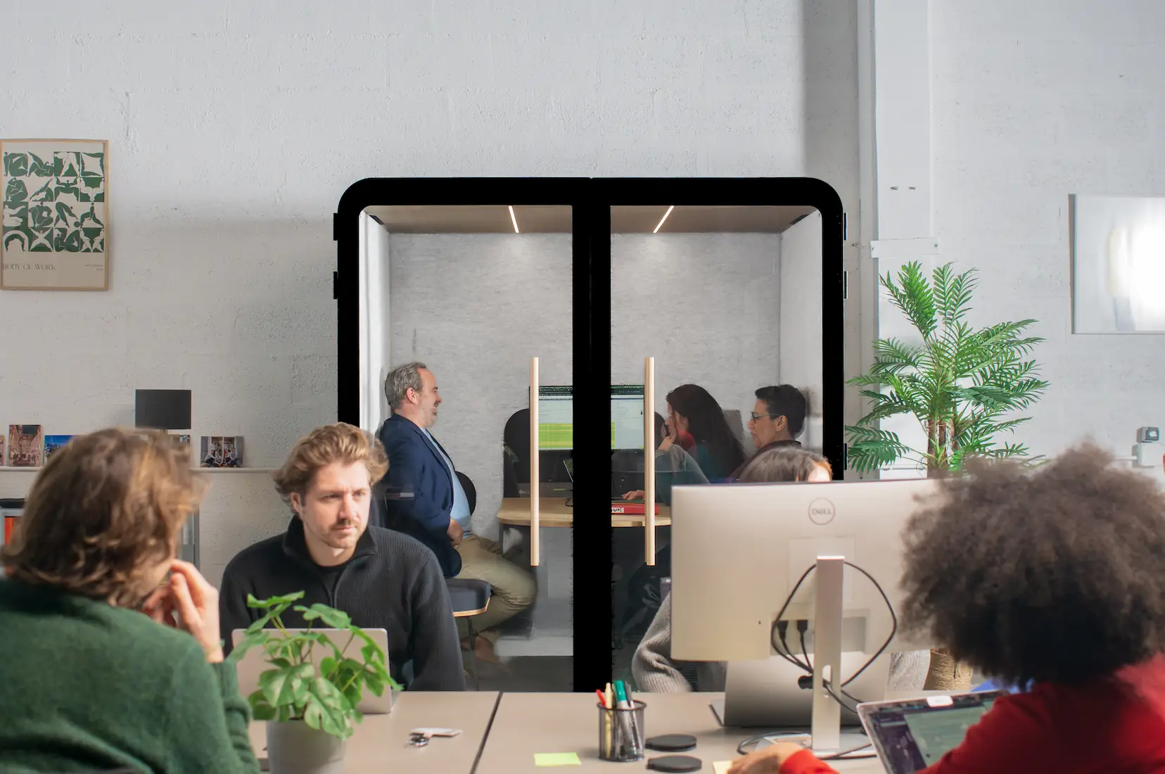 Cabine acoustique Island Quattro noire en open space, avec des collaborateurs travaillant à l'intérieur et autour