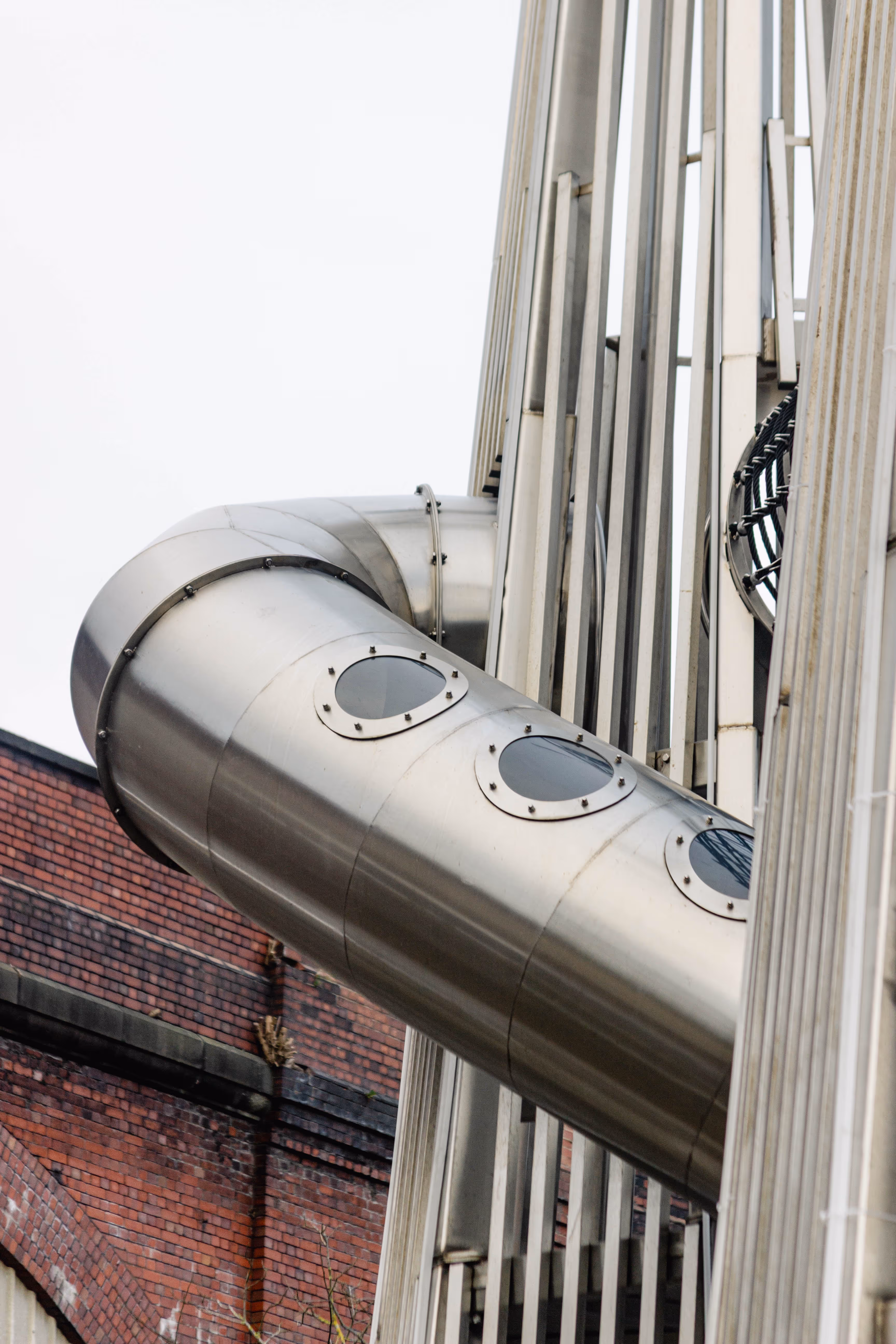 Close-up of bespoke spiral slide featuring viewing windows in stainless steel structure