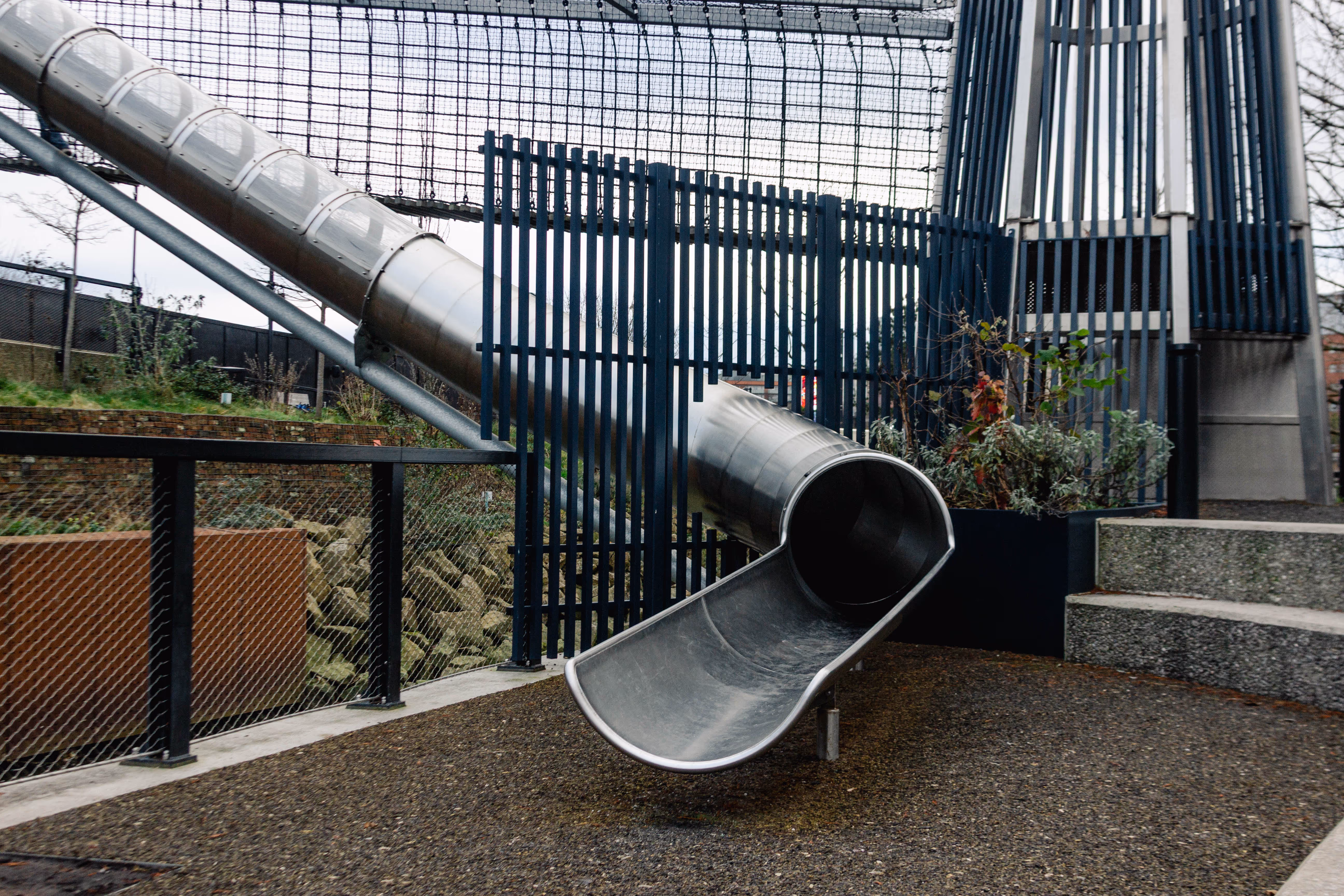 Enclosed river tunnel slide with viewing windows forming part of bespoke playground experience