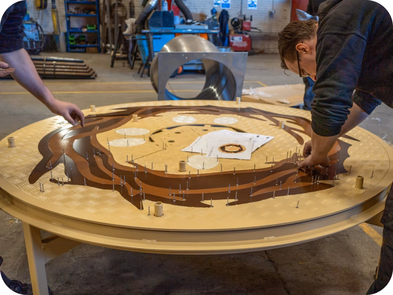 Bespoke bird’s nest themed roundabout being assembled in a Stockport workshop with decorative panels fitted to powder-coated steel base