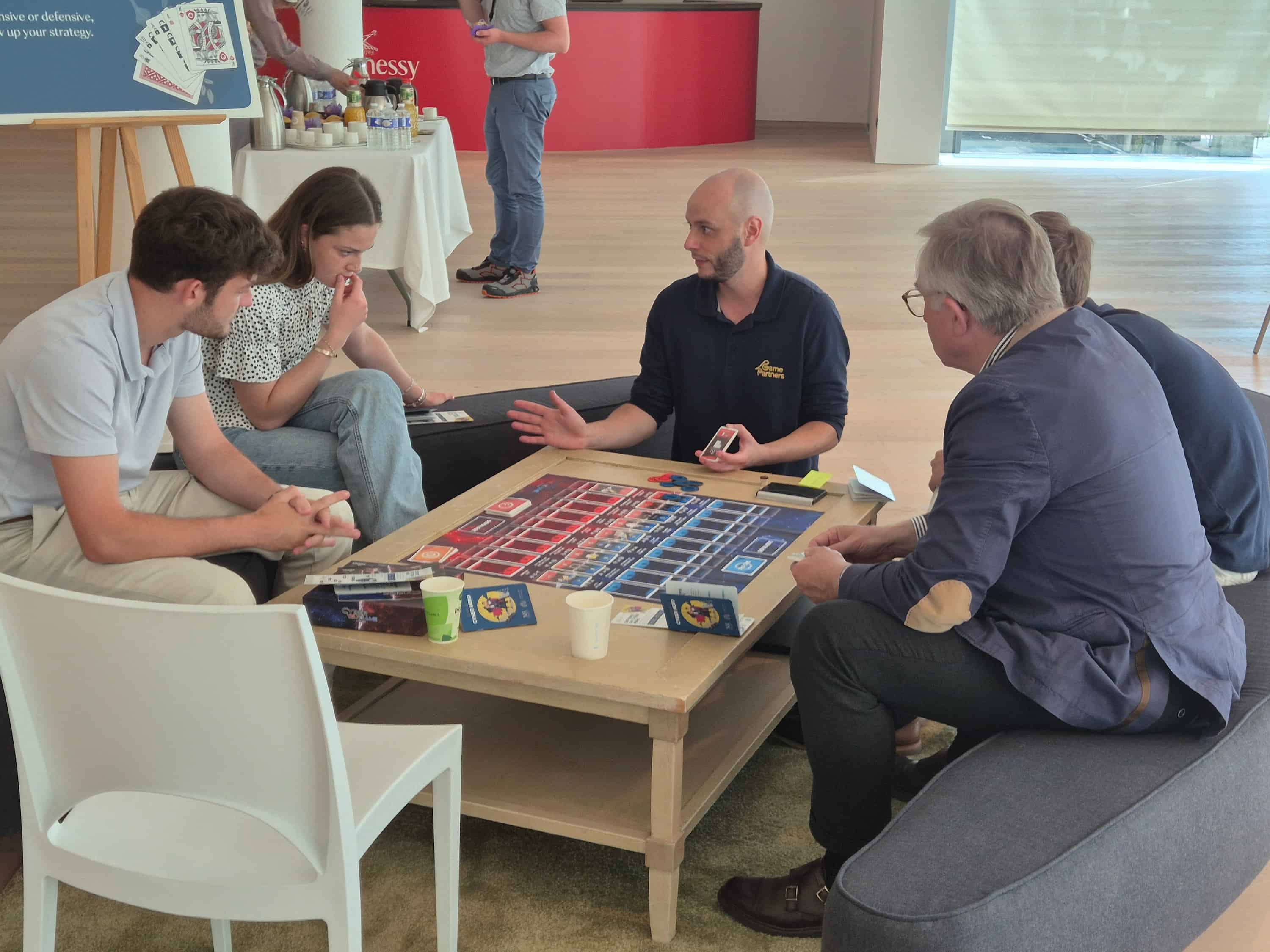 Photo d’Ugo Dorain, spécialiste de l’animation chez Cyber Wargames, animant une session de serious game sur une table basse pour sensibiliser à la cybersécurité.