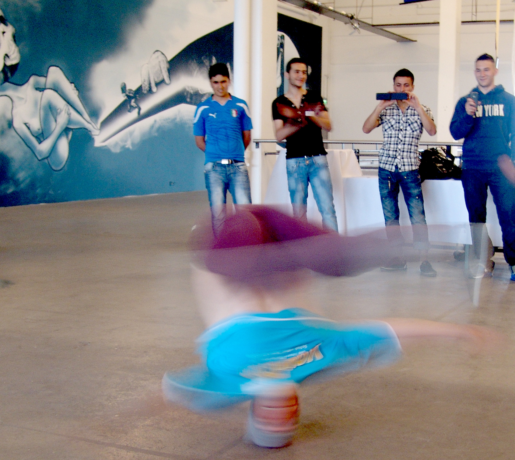 Ein junger Mann beim Breakdancen in einer Sporthalle.