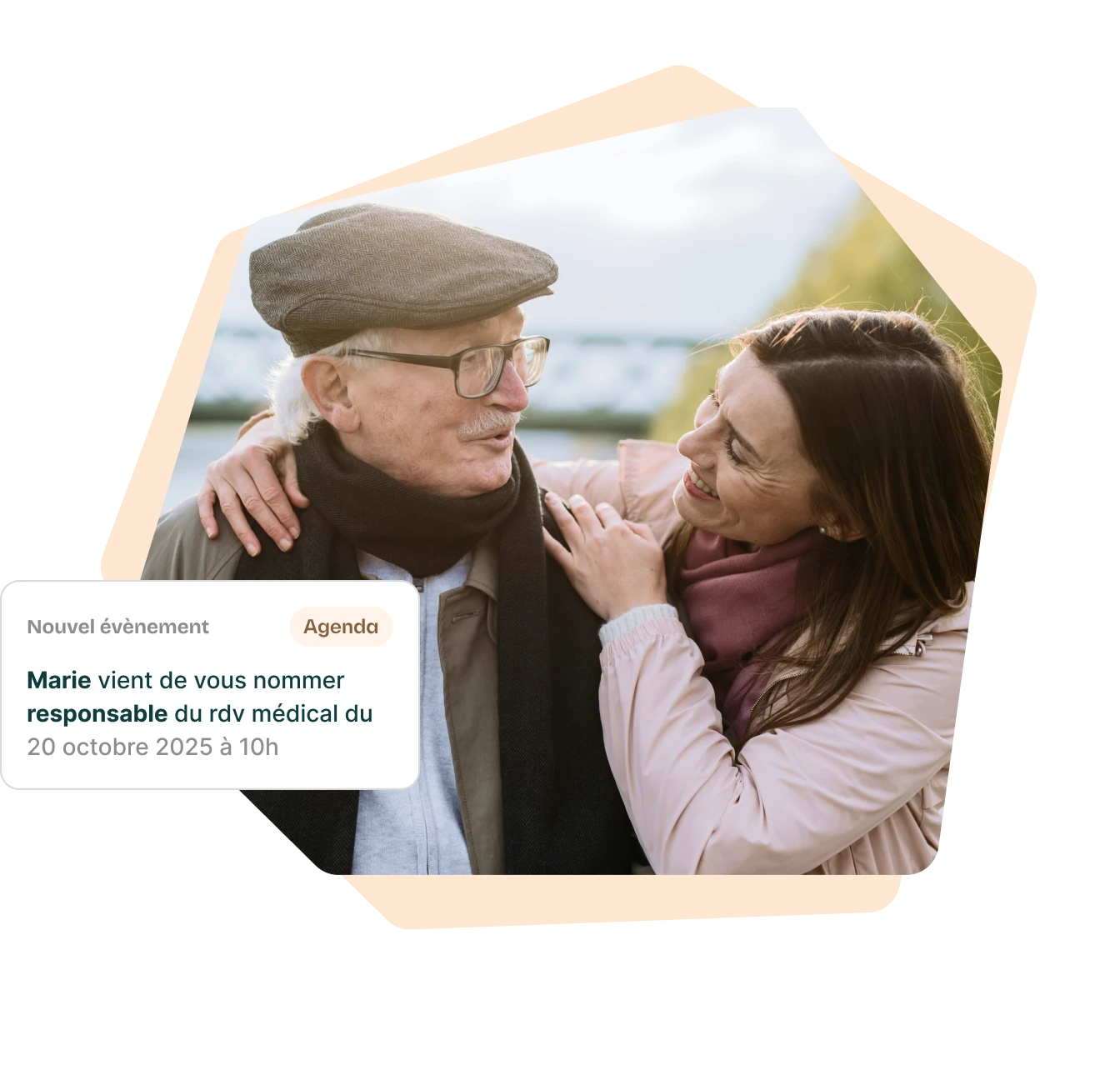 Une femme souriante en manteau clair et foulard rose enlace un homme âgé portant une casquette, des lunettes et une écharpe noire lors d'une promenade extérieure.