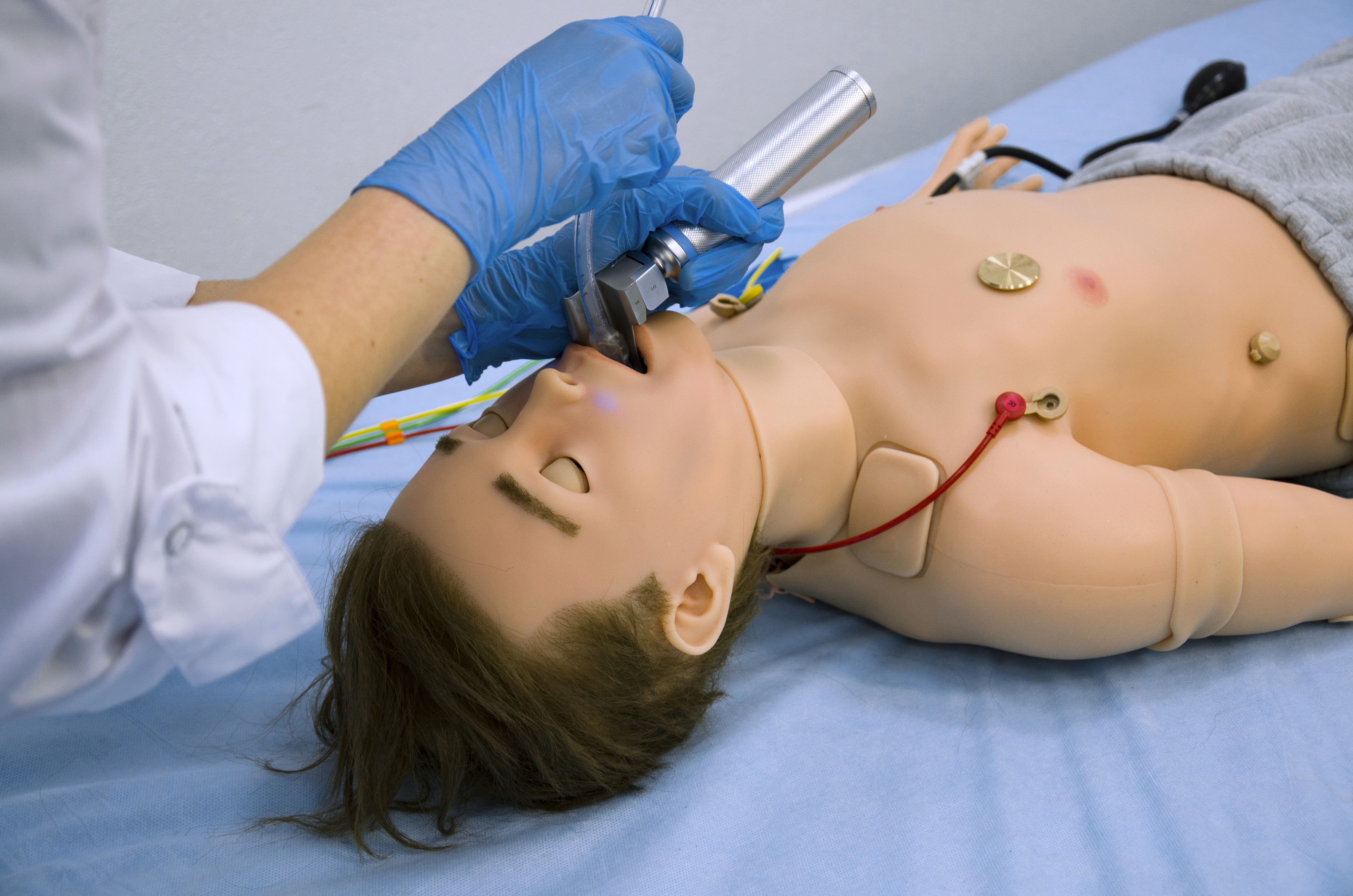 people in medical scrubs doing CPR on a medical simulation manikin