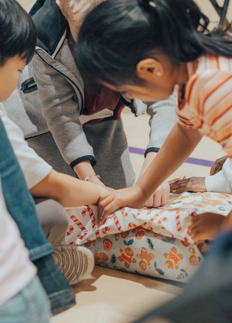 Group of people putting hands together on colorful wrapped gift