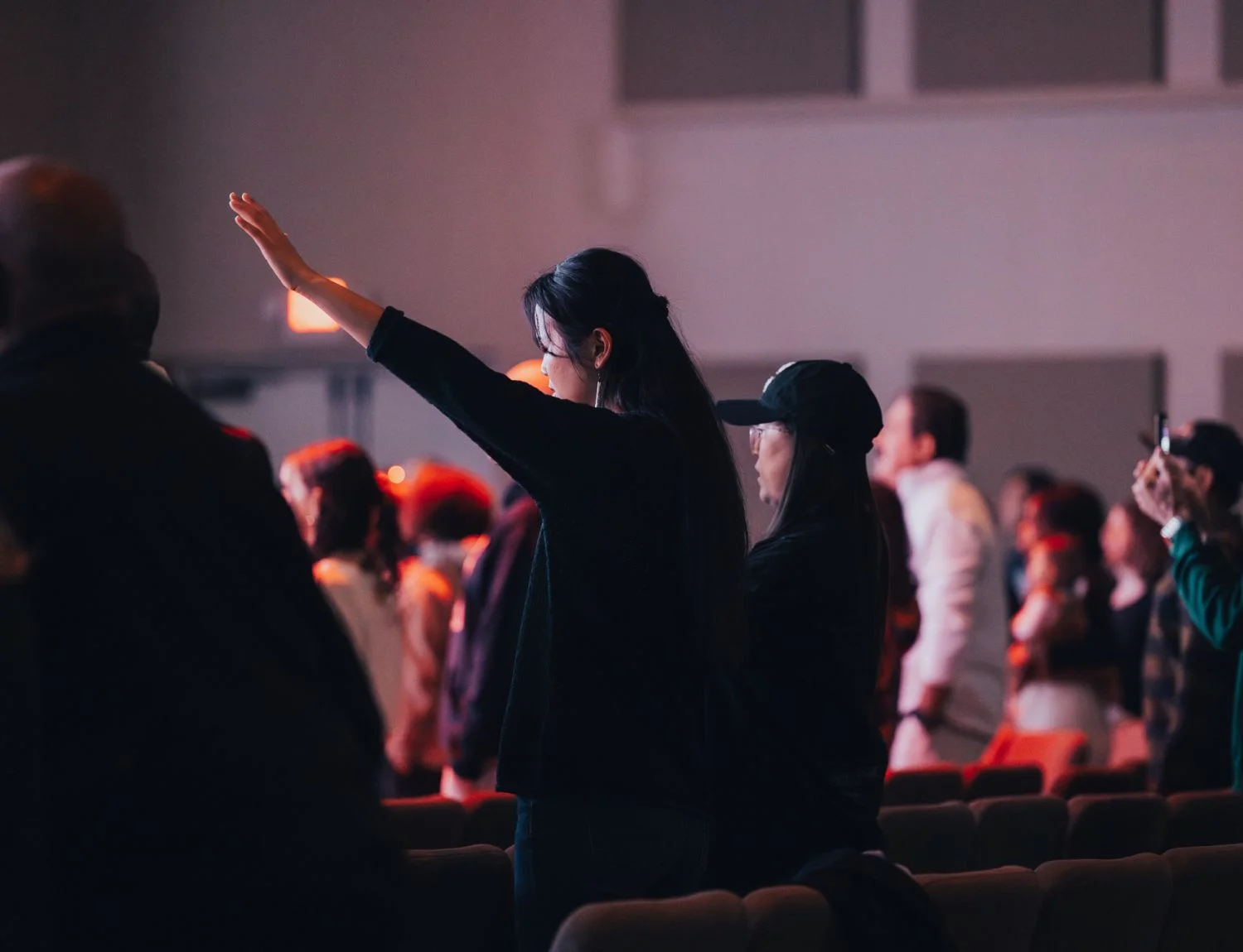 Person raising hand during event in crowded indoor venue